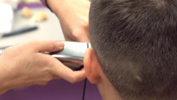Перукар розрізає волосся за допомогою затискача на голові чоловіка. Вид ззаду, стилісти руки крупним планом . — стокове відео
