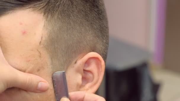 Barberaren rakar håret på män tempel med en vass rakhyvel. Stylister händer närbild. — Stockvideo