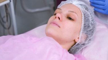Tedavide kanepede yatan klinikte şapkalı kadın.