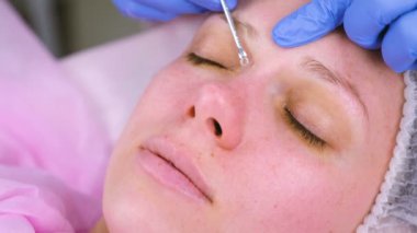 Mekanik Şevval özçelik güzellik, yüz temizleme. Güzellik uzmanı hasta tıbbi iğne yüzünde sivilce sıkmak.