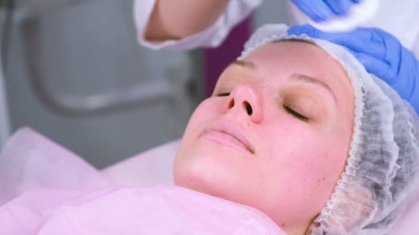 Kosmetolog tvättar kvinnans ansikte med hjälp av bomullsrondeller. Förbereda för en rengöring ansikte. — Stockvideo