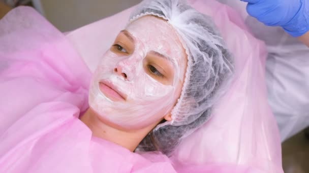 Cosmetologist puts a plastic film on top of the moisturizing mask on the womans face. — Stock Video