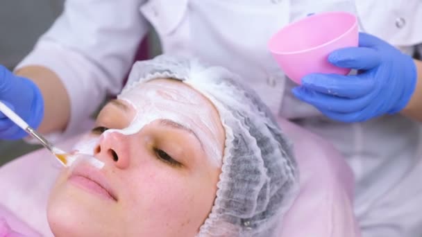 Cosmetologist βάζει μάσκα στο γυναικείο πρόσωπο με βούρτσα. Ενυδάτωση προσώπου. Face close-up. — Αρχείο Βίντεο