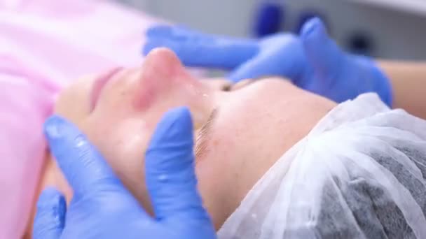 Косметолог наносить крем для зволоження на обличчя жінок. Крупним планом обличчя . — стокове відео