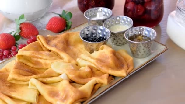 전통적인 러시아 팬케이크, 팬케이크 잼, 크림, 그리고 접시에 딸기와 함께 제공 됩니다. 클로즈업 보기. — 비디오