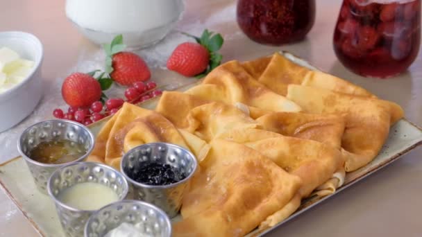 Russian traditional pancakes, blini served with jams, sour cream and strawberry on the plate. Close-up view. — Stock Video
