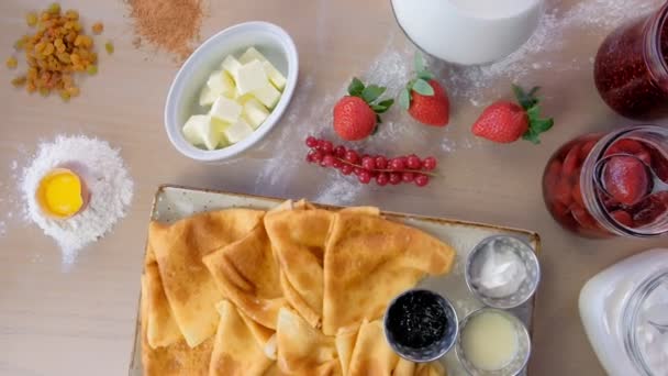 Ryska traditionella pannkakor, blini serveras med sylt, gräddfil och jordgubb på plattan. Närbild ovanifrån. — Stockvideo