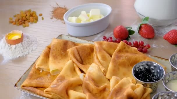 俄罗斯传统的煎饼, 在盘子里放了果酱、酸奶油和草莓。特写镜头侧面视图. — 图库视频影像