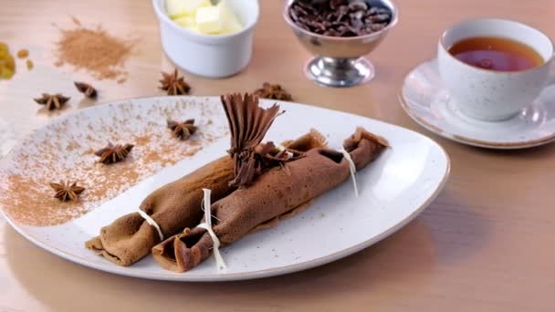 Panqueques rusos de chocolate, blini con relleno de cuajada en el plato. Servido con una taza de té y chocolate . — Vídeo de stock