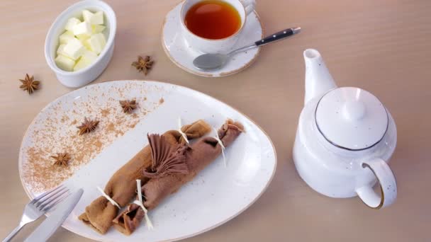 Frittelle russe al cioccolato, blini con ripieno di cagliata sul piatto. Servito con una tazza di tè e burro . — Video Stock