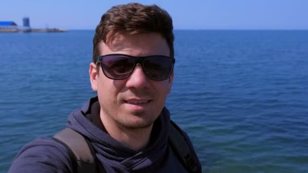 Portre adam video sohbetleri deniz plajında selfie akıllı telefon ve deniz gülümsüyor gösterir. — Stok video