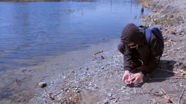 Niño sostiene en las manos poco rana y la deja ir en el río . — Vídeo de stock