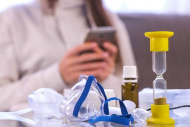 İnhalasyon için hazırlık. Nebulizatör, maske ve tıp cam masanın üzerinde. Unrecognazable kadın ile hareket eden telefon.