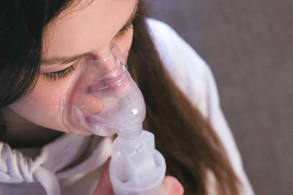 Vernebler und Inhalator für die Behandlung verwenden. junge Frau inhaliert durch Inhalationsmaske. Nahaufnahme von Nase und Lippen in Maske, Draufsicht. — Stockfoto