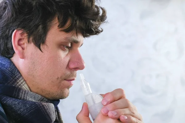 Homem doente inalando através do bocal do inalador para o nariz. Cara fechada, vista lateral. Use nebulizador e inalador para o tratamento . — Fotografia de Stock