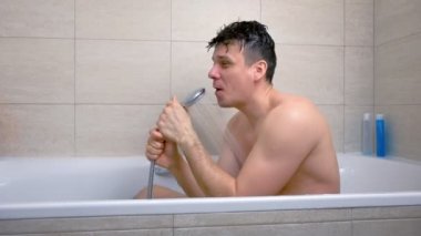 Adam küvette yıkanırken şarkı söylüyor. Duşla kafasına su döküyor..