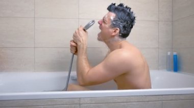 Mohawk şampuan kılları ile Mutlu adam o küvette yıkanırken şarkı söylüyor.