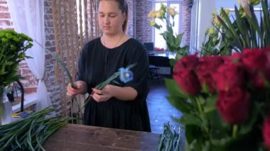 Kadın çiçekçi iris çiçekleri ile çalışır gözyaşları dükkanda bırakır demet için hazırlar.