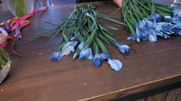 Florista mulher fazendo buquê de flores de íris azul na mesa para venda na loja . — Vídeo de Stock