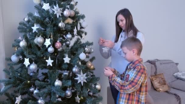 Μαμά και γιός διακόσμηση τεχνητό χριστουγεννιάτικο δέντρο στο σαλόνι στο σπίτι μαζί. — Αρχείο Βίντεο