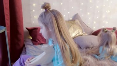 Küçük kız kardeşi oyuncak ile yatakta oturan ablası genç sarılma.