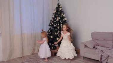 Noel ağacı yakınında birlikte dans güzel beyaz elbiseler iki kız kardeş.