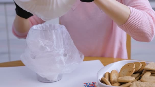 Womans kezét fel a cukor édes jegesedés a zsákban a tálat díszítő cookie-kat és mézeskalács házak. Főzés házi mézeskalács ház. — Stock videók