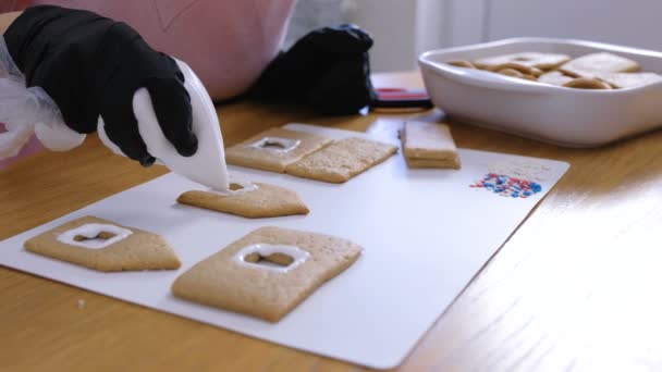 Frauenhände dekorieren zuckersüße Puderkekse für Lebkuchenhäuser. Kochen hausgemachte Lebkuchen Haus. — Stockvideo