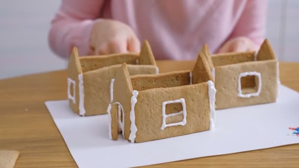 Womans hands make gingerbread houses glues details with sugar sweet icing. Cooking homemade gingerbread house. — Stock Video