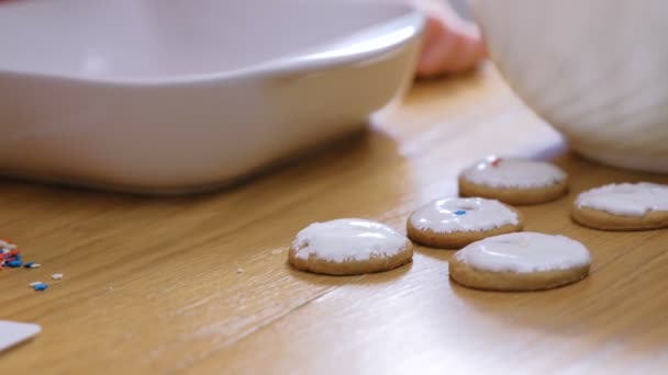 Τα χέρια των βοιτών διακοσμούν Χριστουγεννιάτικα μπισκότα με γλυκό γλάσο ζάχαρης. — Αρχείο Βίντεο