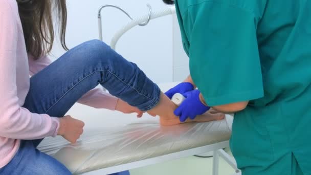 Kirurg slingrande bandage på kvinna ben efter operation för att avlägsna fotled hygroma. — Stockvideo
