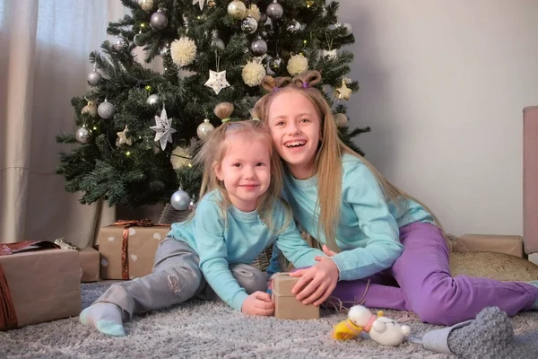 Lächelnde Mädchen posieren für ein Foto in der Nähe des Weihnachtsbaums und schauen in die Kamera. — Stockfoto