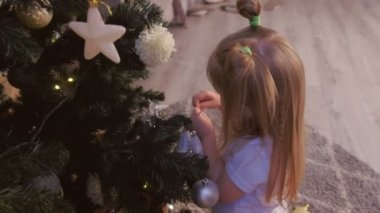 Sevimli çocuk kız evde oyuncaklar ile yapay Noel çam ağacı dekore.