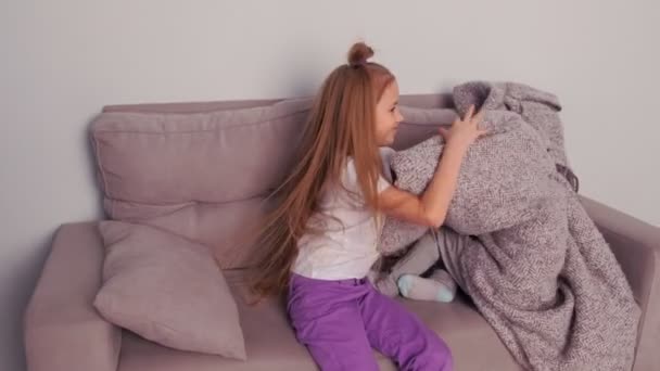 Duas irmãs brincando de esconder e procurar sentado no sofá escondido sob xadrez . — Vídeo de Stock