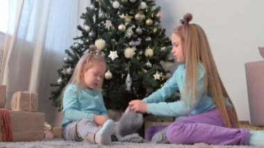 İki kız kardeş Noel ağacının yanında el yapımı oyuncaklar ve örgü çoraplar oynuyor..