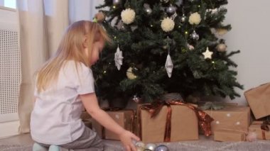 Küçük kız oyuncak yıldızları Noel ağacı oyunlarından topları alıyor..