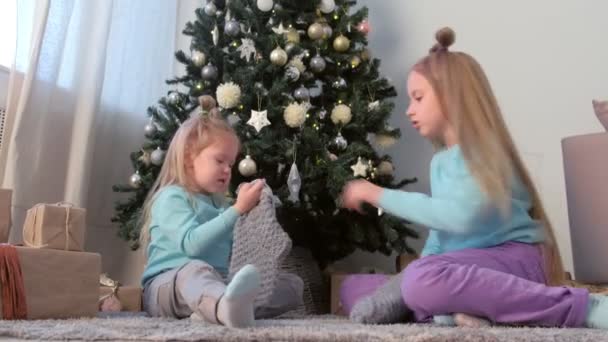 Dos hermanas jugando witn juguetes hechos a mano y calcetines de punto cerca del árbol de Navidad . — Vídeos de Stock