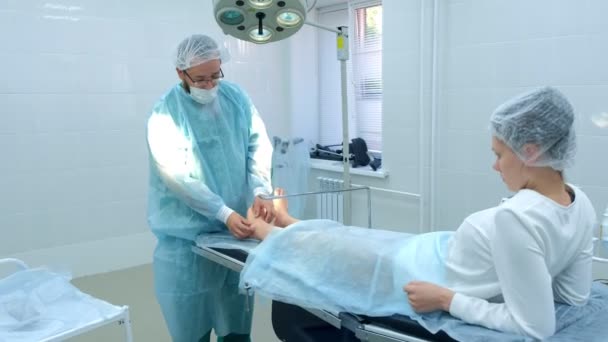Χειρουργός ψηματίζει το πόδι πριν από τη χειρουργική επέμβαση για να αφαιρέσει το υγρόμωμα του αστραγάλου σε κοινή, κοντινό πλάνο. — Αρχείο Βίντεο