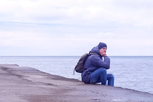 Man Traveller sitter på gamla vattnet till sjöss på vintern dag och tittar på Seascape. — Stockfoto