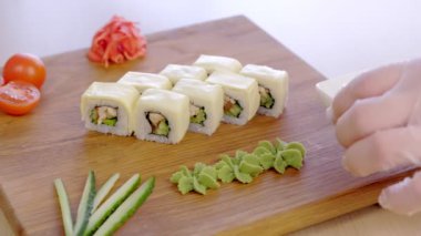 Cook wasabi, marine, kırmızı zencefil, soya sosu ve sebze ile ahşap tahta üstüne tavuk, salatalık, yeşillik ve krem satranç ile rulo hizmet vermektedir.