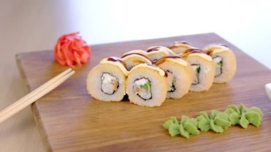 Ahşap tahta üzerinde wasabi, kırmızı zencefil ve soya sosu ile servis rulo.