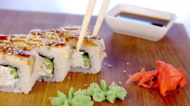 Kadın üstte ahşap tahta wasabi, zencefil ve soya sause ile servis balık ve susam tohumu ile rulo yiyor. Eller yakın çekim.