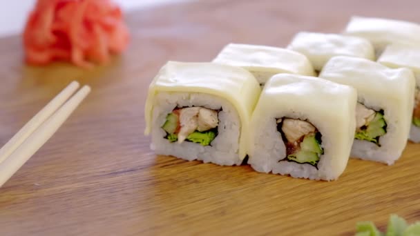 Rouleaux avec poulet, concombre, légumes verts et crème d'échecs sur le plateau en bois avec wasabi, mariné, gingembre rouge. Vue latérale . — Video