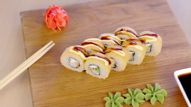 Rouleaux servis sur planche de bois avec wasabi, gingembre rouge et sauce soja, vue latérale rapprochée . — Video