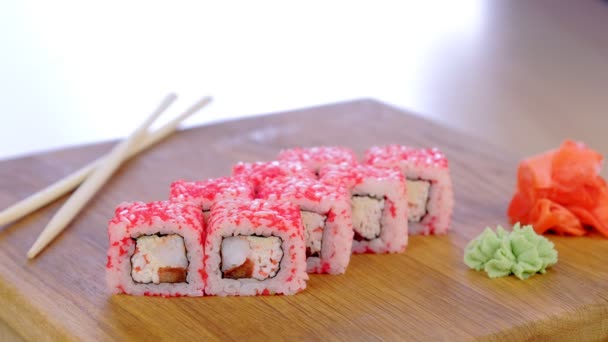 Kok serveert rollen met vis, garnalen en rode kaviaar op de top op een houten bord met wasabi en sojasaus. — Stockvideo