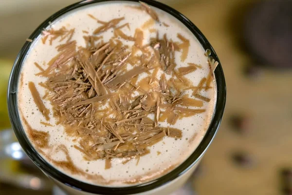 Irish coffee with grated chocolate and straw. Close-up top view. — Stock Photo, Image