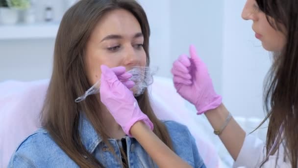 Il cosmetologo medico mette il film plastico su crema con anestesia su labbra di donna . — Video Stock