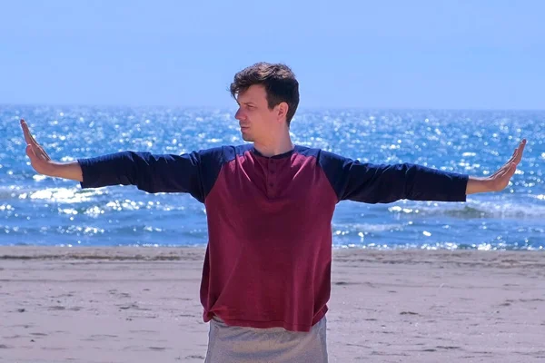 De mens is aan het opwarmen op het strand voor de yoga praktijk. — Stockfoto