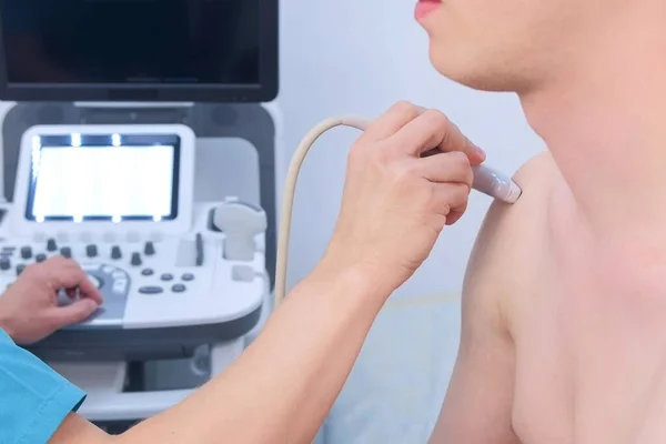 Doctor makes ultrasound of shoulder joint man using ultrasound scanner, closeup.