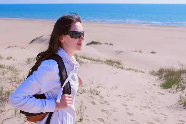 Woman traveller with backpack is looking around in sea sand beach on vacation.